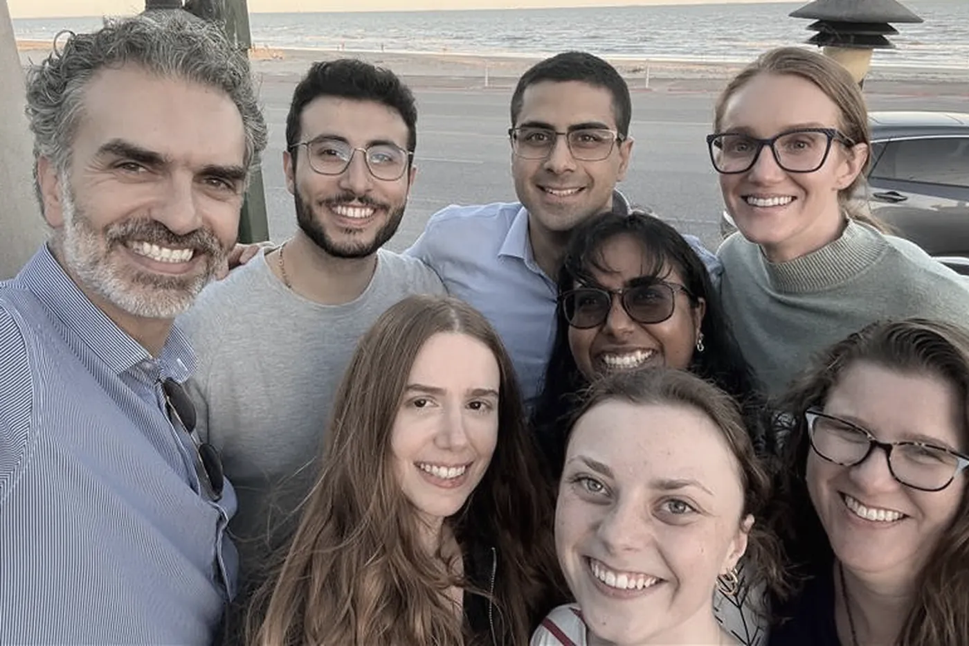 Eight members of the Hayek Lab outdoors by the water in Galveston