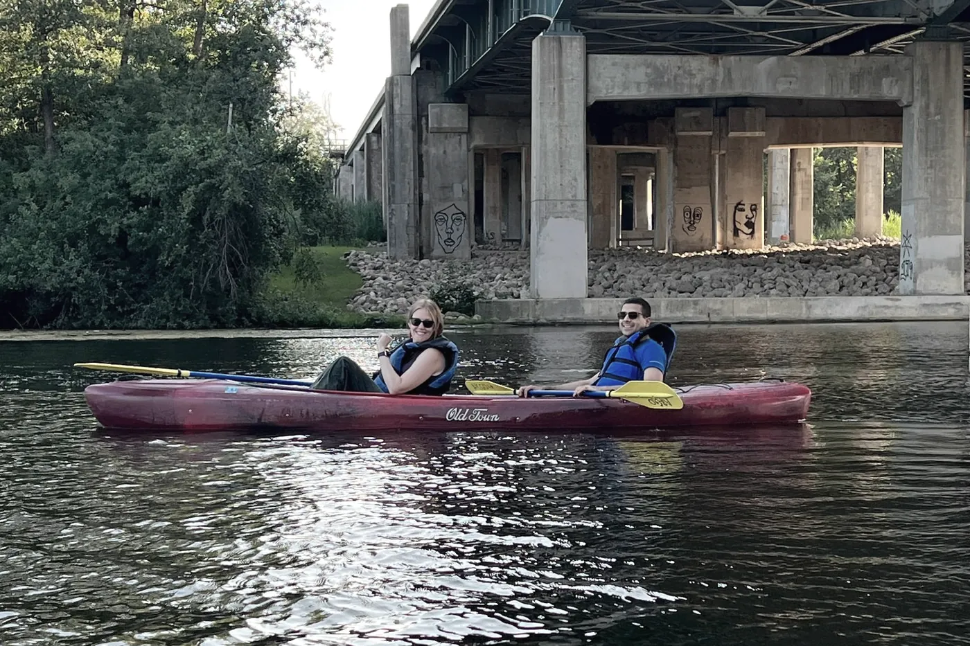 Two lab members kayaking on a river beneath a bridge