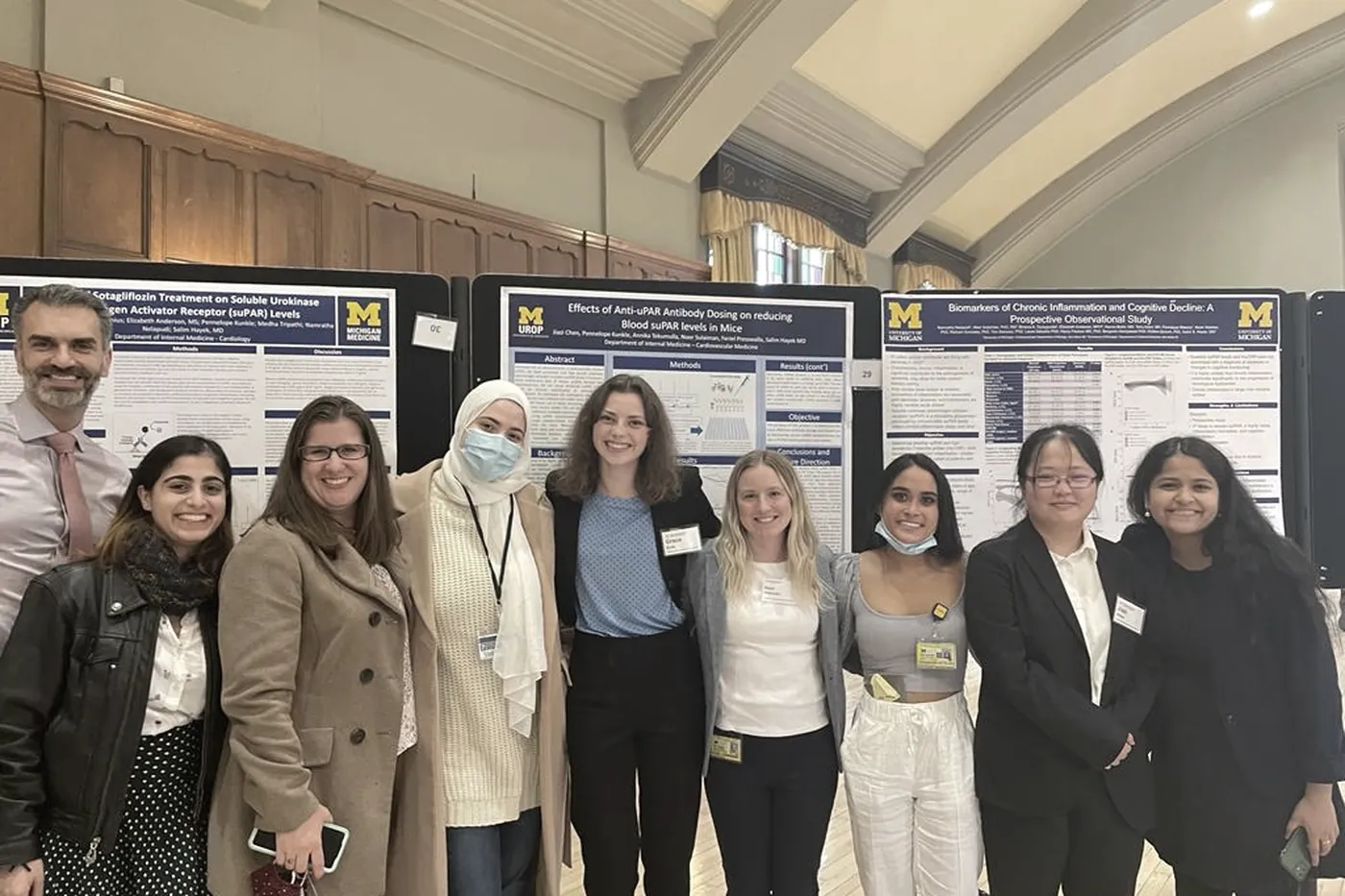 Lab members standing in front of their research posters at a symposium